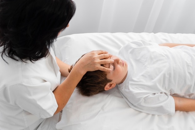 Osteopata tratando um menino massageando sua cabeça