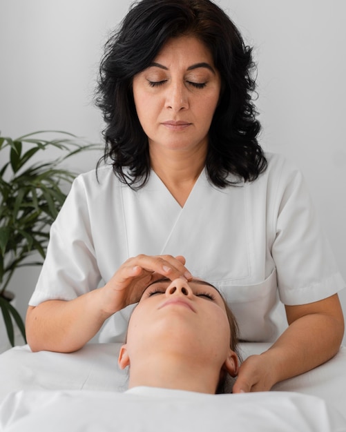 Foto grátis osteopata tratando um paciente massageando seu rosto