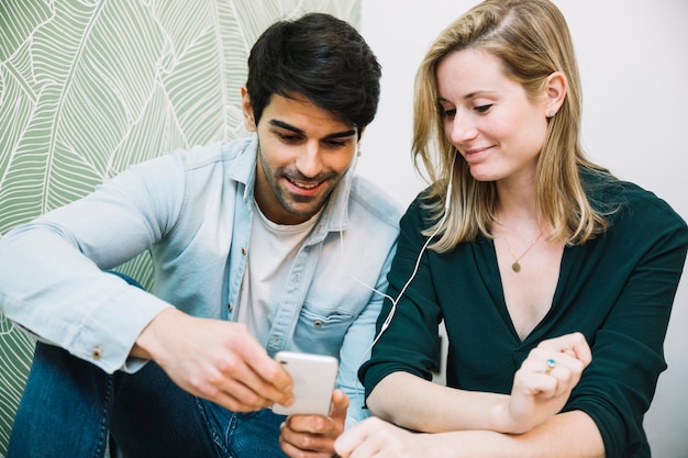 Foto grátis ouple partilha fones de ouvido olhando para smartphone