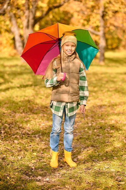 Outono. Uma garota com um guarda-chuva brilhante em um parque de outono