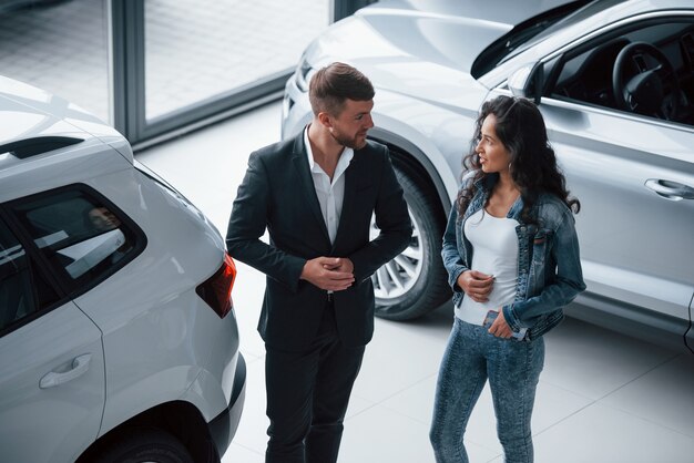 Ouvindo com atenção. Cliente do sexo feminino e empresário barbudo elegante e moderno no salão automóvel