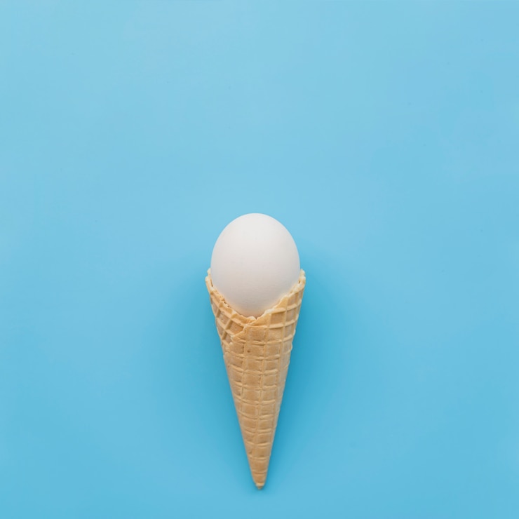 Foto grátis ovo branco em chifre de waffle em fundo azul