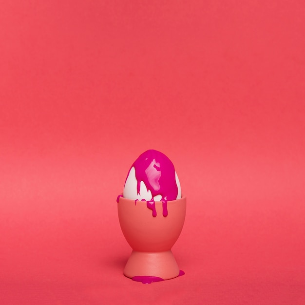 Foto grátis ovo de cópia-espaço em suporte com tinta roxa