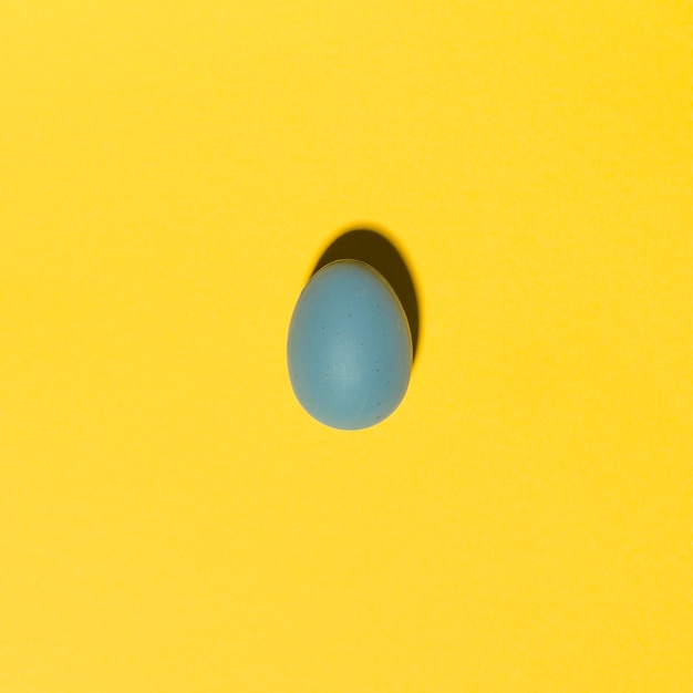 Ovo de páscoa azul na mesa amarela