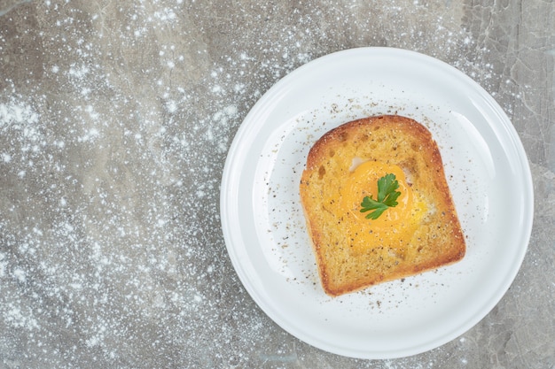 Ovo frito dentro de uma fatia de pão torrado no prato branco. Foto de alta qualidade