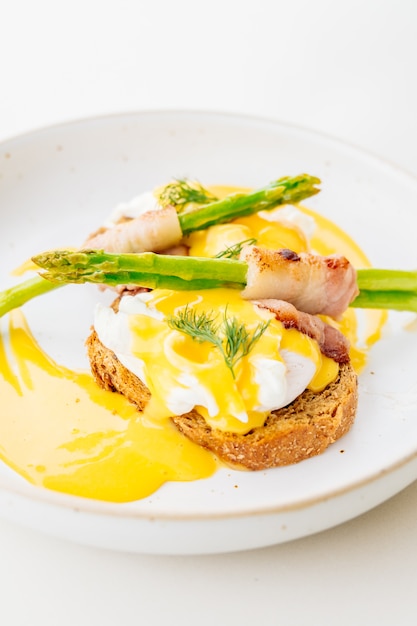 Ovos benedictos com bacon, espaguete e espargos.
