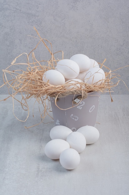 Ovos brancos frescos em um balde com fundo de mármore.
