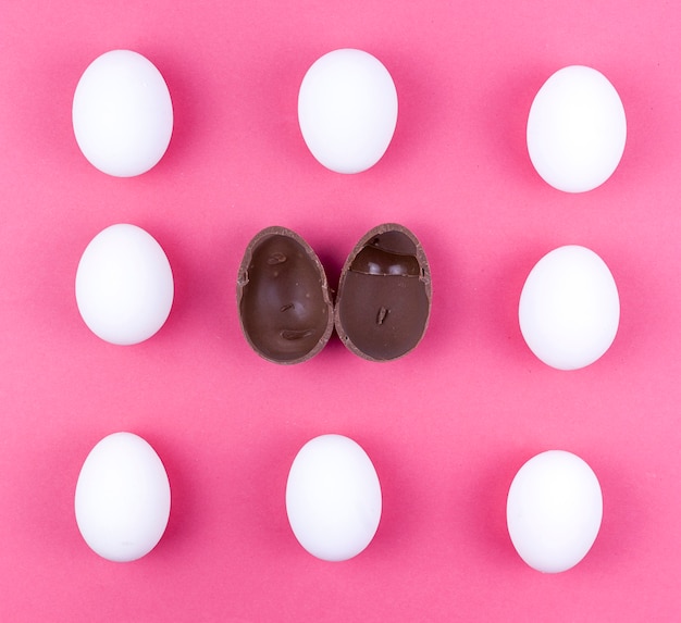 Ovos de galinha branca com ovo de chocolate aberto na mesa