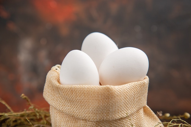 Foto grátis ovos de galinha de frente para dentro do saco na superfície escura