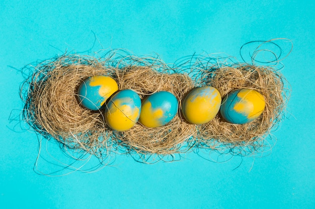 Ovos de Páscoa brilhantes em ninhos na mesa azul