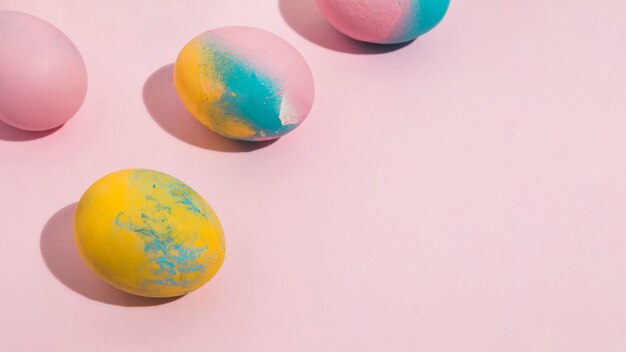 Ovos de Páscoa brilhantes espalhados na mesa-de-rosa