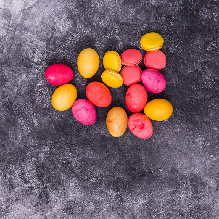 Foto grátis ovos de páscoa coloridos com macaroons na mesa