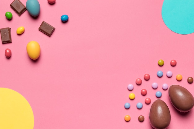 Ovos de Páscoa de chocolate e doces de gema com espaço de cópia para escrever o texto no fundo rosa