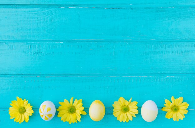 Ovos de Páscoa e flores amarelas na mesa