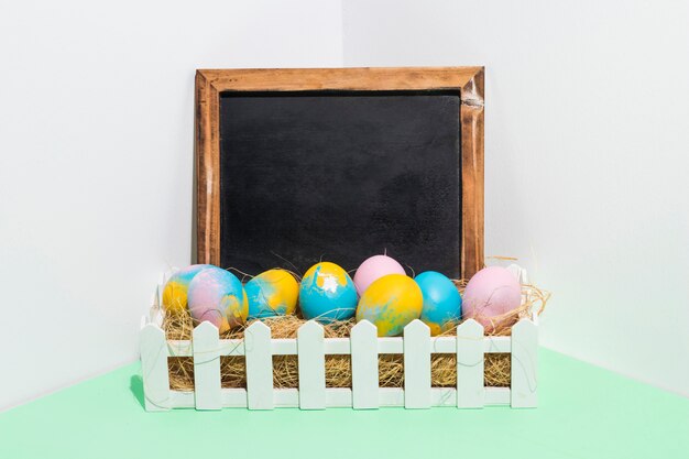 Ovos de Páscoa no feno na caixa com lousa