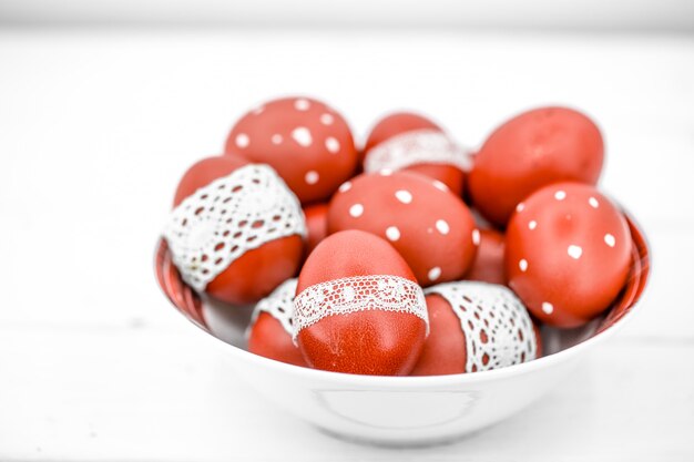 Foto grátis ovos de páscoa vermelhos em um prato branco e em uma fita de renda branca amarrada, close-up
