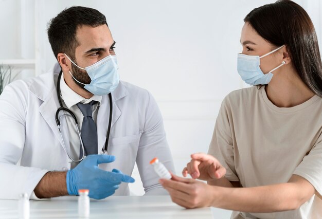 Paciente conversando com o médico usando máscaras médicas