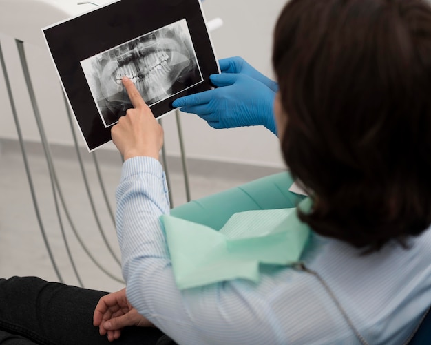 Paciente do sexo feminino olhando para uma radiografia de dentes com um dentista