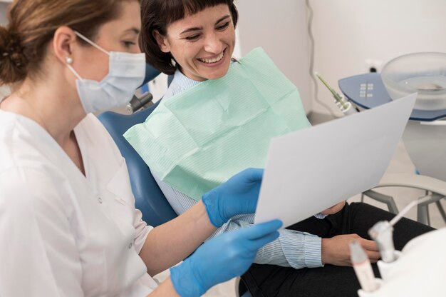 Paciente do sexo feminino olhando para uma radiografia de dentes com um dentista