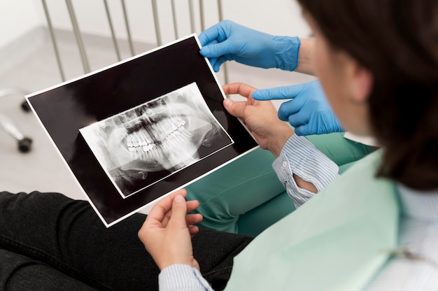 Paciente do sexo feminino olhando para uma radiografia de dentes com um dentista