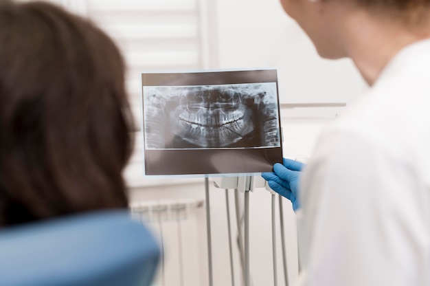 Paciente do sexo feminino olhando para uma radiografia de dentes com um dentista