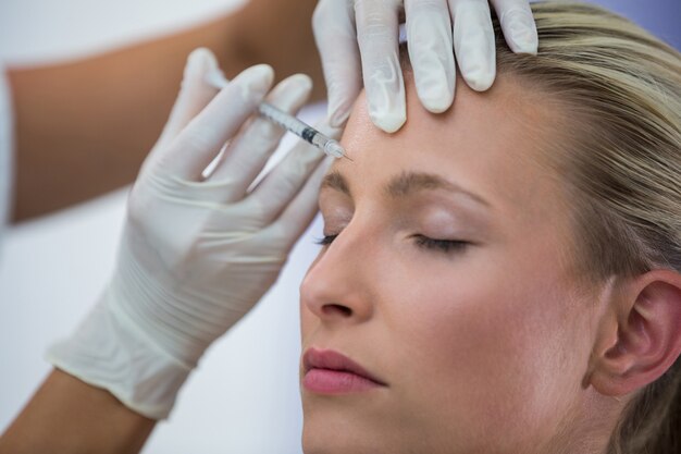 Paciente do sexo feminino recebendo uma injeção de botox na testa