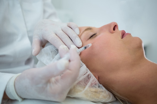 Paciente do sexo feminino recebendo uma injeção de botox no rosto