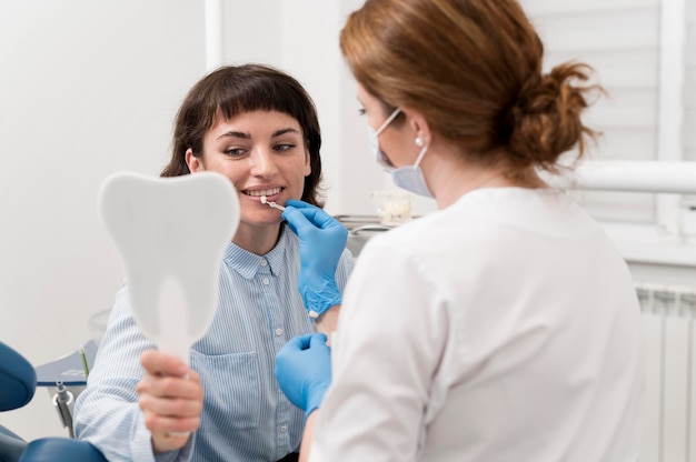 Paciente do sexo feminino se olhando no espelho do consultório dentista