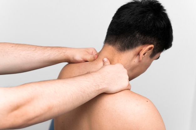 Paciente do sexo masculino recebendo massagem no pescoço do fisioterapeuta