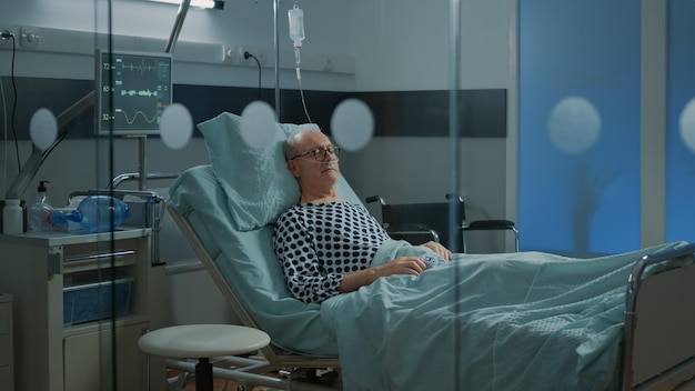 Foto grátis paciente doente dormindo em cama de enfermaria de hospital em unidade de saúde com tubo de oxigênio nasal para problemas respiratórios. velho doente à espera de tratamento médico para recuperar da doença