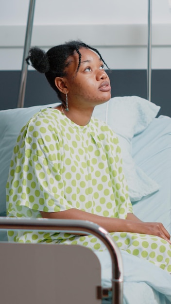 Foto grátis paciente doente esperando médico para dar tratamento e apoio enquanto está sentado na cama da enfermaria do hospital. mulher com doença recebendo cuidados médicos na clínica com monitor de frequência cardíaca e bolsa de gotejamento iv