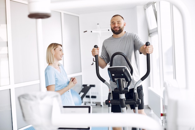 Paciente fazendo exercício em bicicleta de spin no ginásio com terapeuta