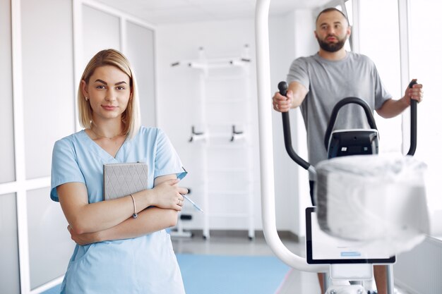 Paciente fazendo exercício em bicicleta de spin no ginásio com terapeuta