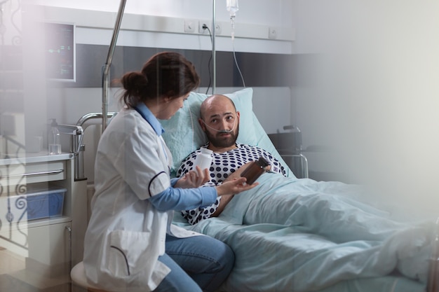 Foto grátis paciente homem doente com tubo de oxigênio nasal descansando na cama durante exame médico na enfermaria do hospital ...