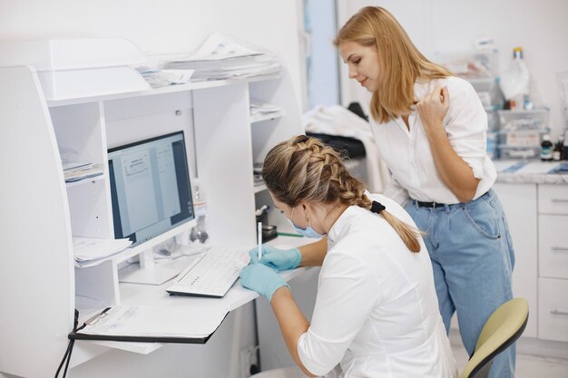 Paciente mulher no consultório médico. Doutor em máscara médica. O médico usa o computador.