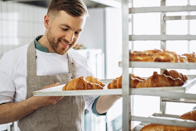 Padeiro de homem segurando croissants na padaria