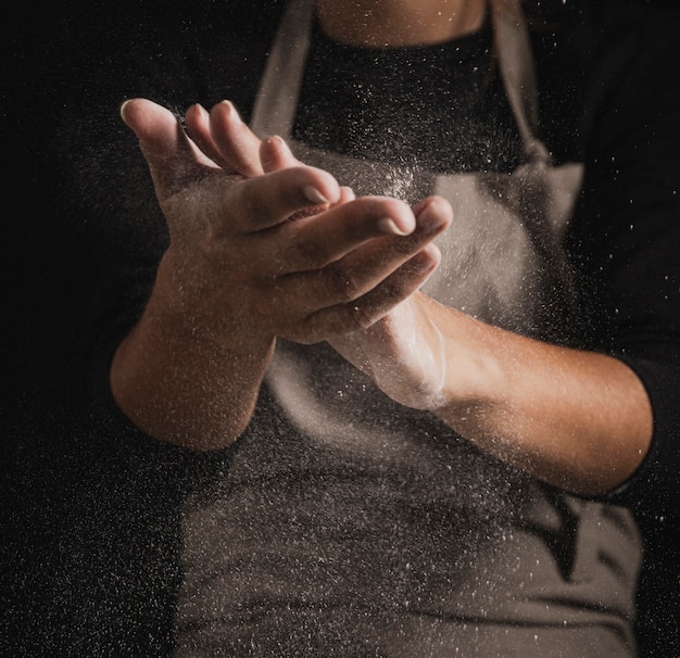 Foto grátis padeiro do close-up que limpa as mãos fora da farinha