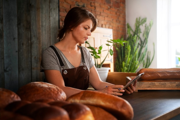 Foto grátis padeiro feminino usando tablet na confeitaria