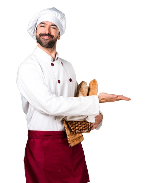 Padeiro jovem segurando um pouco de pão e apresentando algo