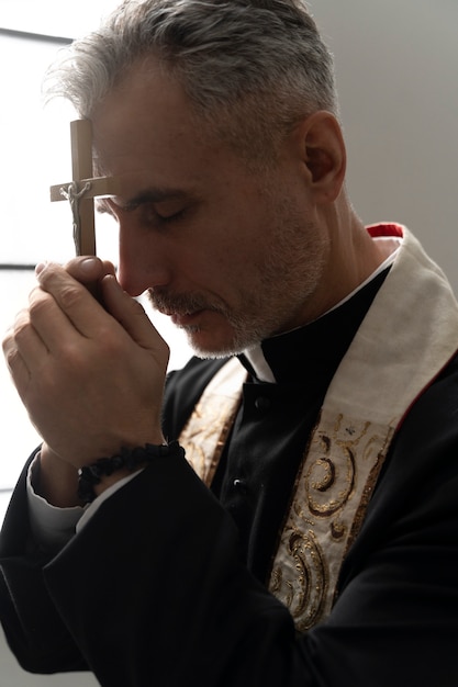 Padre cristão de tiro médio rezando com crucifixo