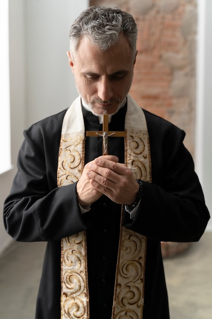 Foto grátis padre de tiro médio rezando com crucifixo