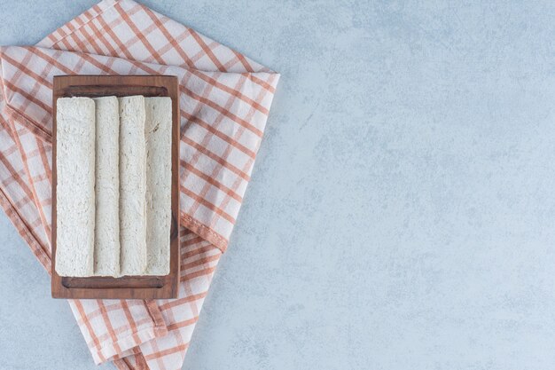 Pães estaladiços no tabuleiro na toalha no mármore.