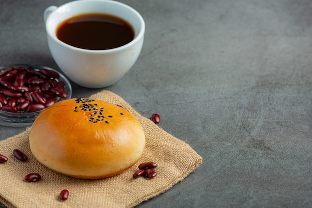 Pãezinhos de pasta de feijão vermelho assados colocados em tecido marrom servido com café