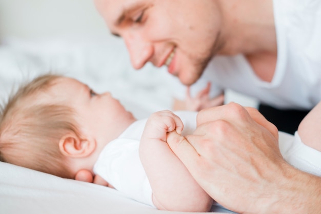 Pai abraçando e olhando para o bebê na cama