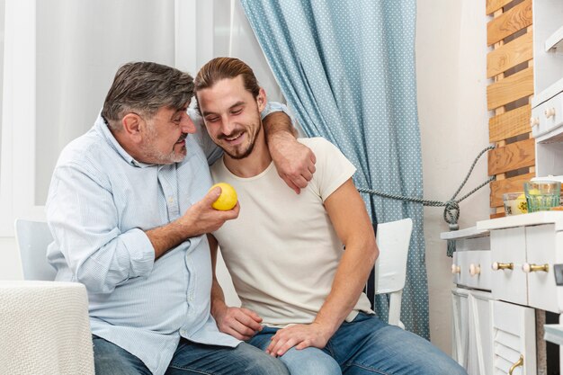 Pai abraçando o filho e segurando uma maçã saborosa