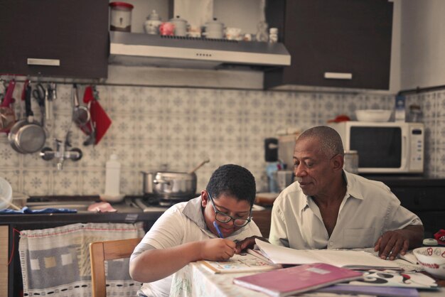 Pai ajuda filho com lição de casa na cozinha