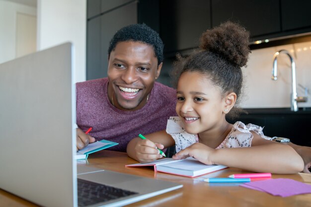 Pai ajudando e apoiando a filha na escola online enquanto fica em casa