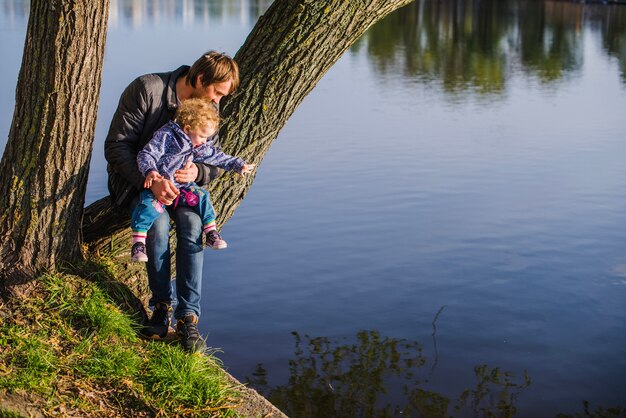 Pai brincando com o filho ao lado do lago