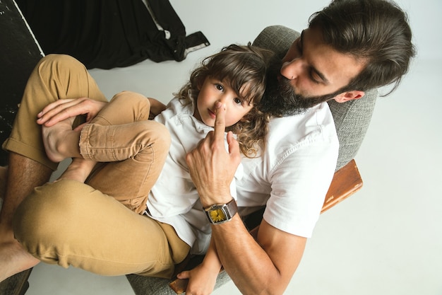 Pai brincando com o filho na sala de estar em casa. jovem pai se divertindo com seus filhos nos feriados ou fim de semana. conceito de paternidade, infância, dia dos pais e relação familiar.