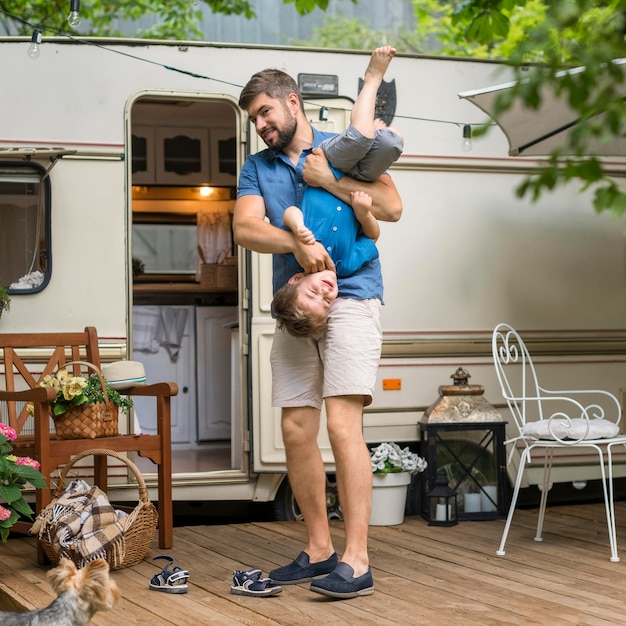 Pai brincando com seu filho ao lado de uma caravana